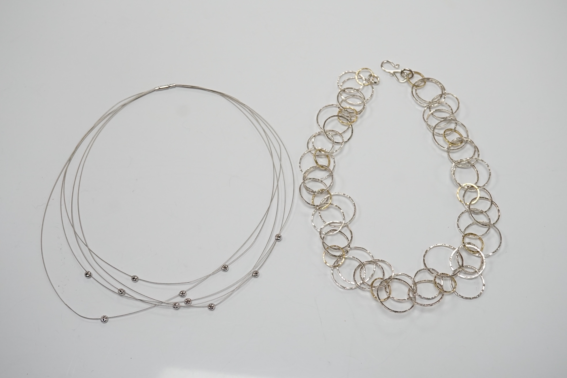 A modern Pruden & Smith silver and yellow metal hoop necklace and a 750 white metal and diamond set multi strand necklet retailed by Mappin & Webb. Condition - fair to good